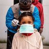 Una trabajadora de salud pone una mascarilla médica a una niña antes de su consulta en Roma, Italia.