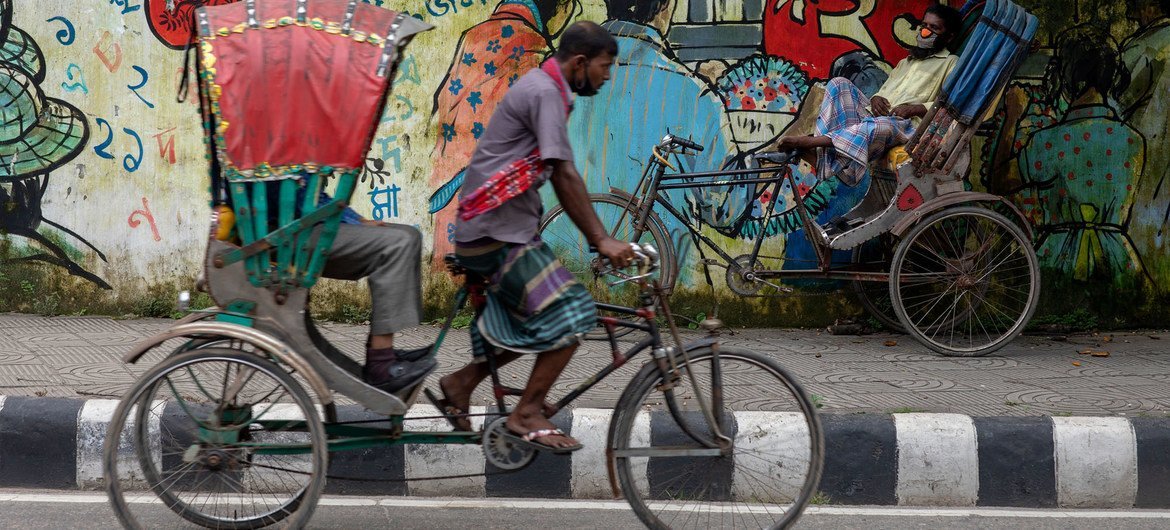 In the middle of a hot day, rickshaw puller Raja Mia (in background with mask) takes a rest on the side of the street in Dhaka, Bangladesh.