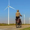 荷兰海宁根，一名妇女骑自行车经过乡村公路上的风力涡轮机。