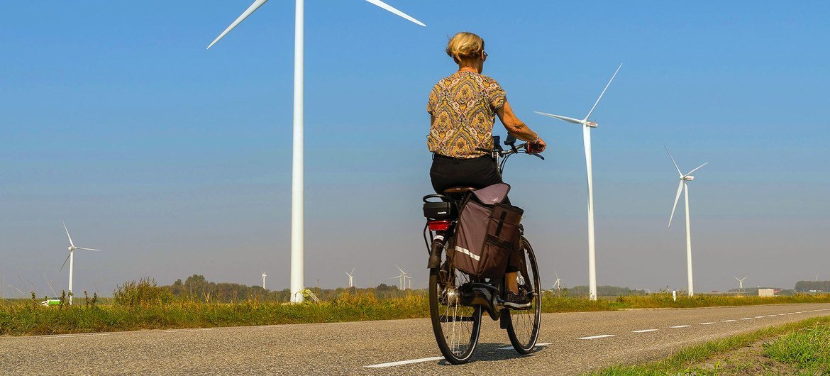 Une femme passe devant des éoliennes sur une route de campagne à Heijningen, aux Pays-Bas.