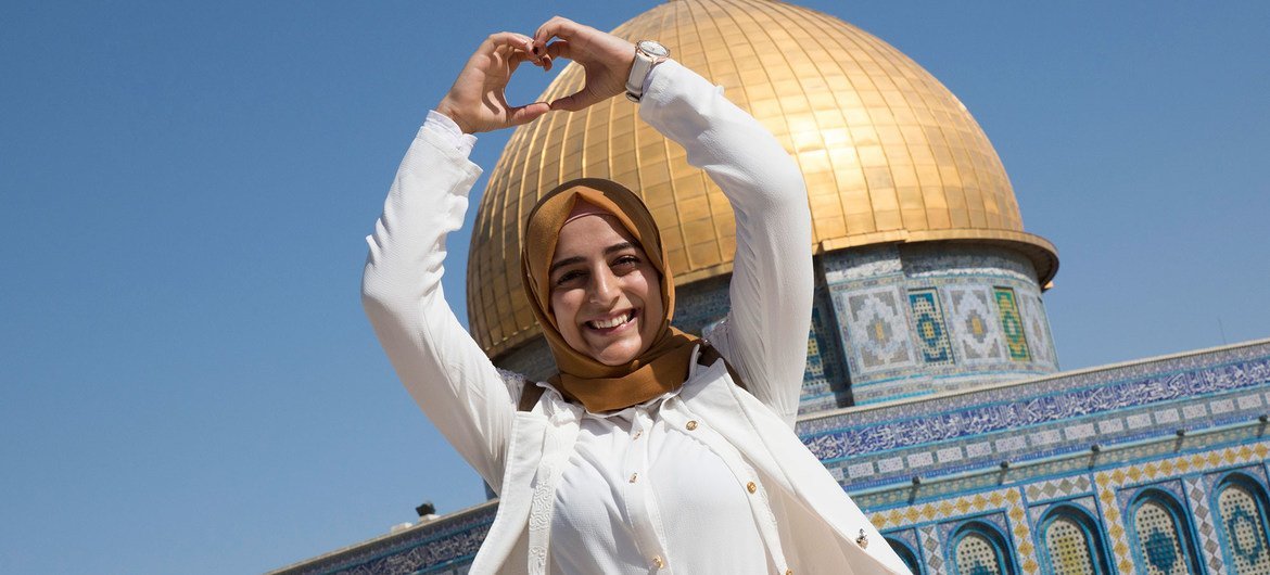 一名首次离开约旦河西岸的巴勒斯坦女孩站在耶路撒冷岩石圆顶清真寺外。