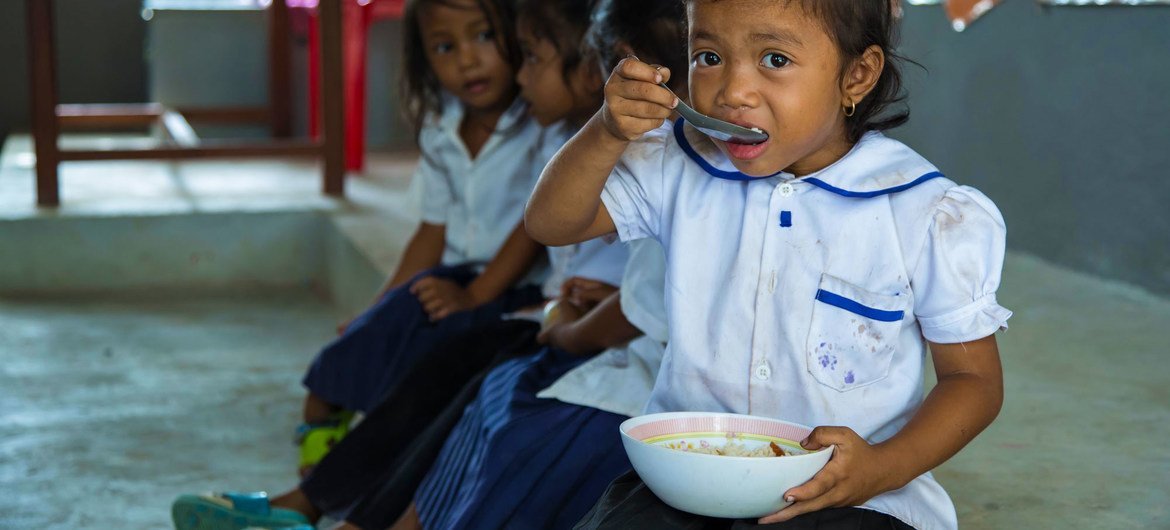 طفلة صغيرة تتناول الطعام في المدرسة قبل بدء الدرس، كمبوديا.