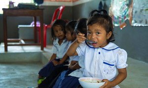 A young girl eats a meal in school before beginning class in Cambodia.