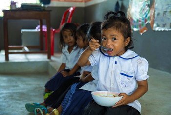 कम्बोडिया एक स्कूल में एक बच्ची, कक्षा शुरू होने से पहले भोजन कर रही है.