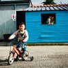 希腊莱斯沃斯岛上的一处难民居住点内，一个男孩正在骑自行车。