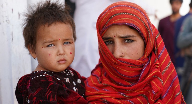 Una niña de doce años junto a su hermanita bebé afuera de un campamento de desplazados internos en Afganistán