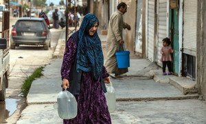 Une mère transporte de l'eau fournie par l'UNICEF dans un camp de fortune en Syrie.