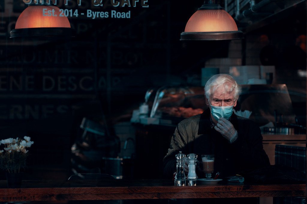 Un hombre lleva una mascarilla y guantes en un café de Glasgow, Escocia.