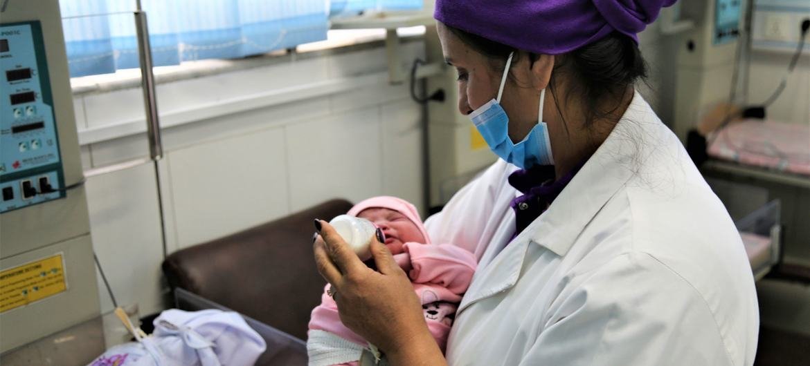 رئيسة القابلات في مستشفى للولادة في كابول تحضر ولادة طفل، أفغانستان.