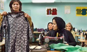 दिल्ली में एक अफ़गान शरणार्थी,गर्व से ख़ुद बनाई एक पोशाक दिखा रही हैं.