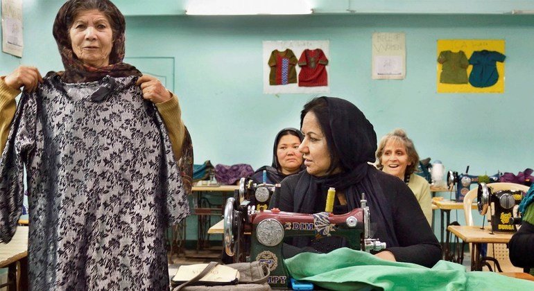 दिल्ली में एक अफ़गान शरणार्थी,गर्व से ख़ुद बनाई एक पोशाक दिखा रही हैं.