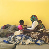 من الأرشيف: أم محتجزة مع طفليها أحدهما نائم على ظهرها والأخر يتناول الخبز من يدها في أحد مراكز الاحتجاز في بنغازي، ليبيا.