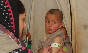 A health worker screens a four-year-old boy for malnutrition at an IDP camp in north-east Syria.