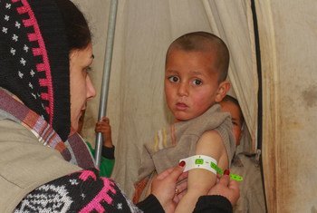 عاملة صحية تفحص طفلاً في الرابعة من عمره لتحقق إذا كان مصابا بسوء التغذية في مخيم للنازحين شمال شرق سوريا.