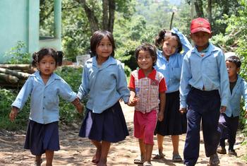 مجموعة من أطفال المدارس يمشون يداً بيد بعد انتهاء دوامهم في المدرسة في أحد أرياف نيبال.