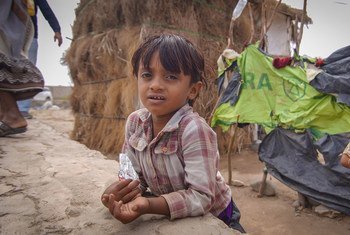 طفل يلهو في وقت تقف والدته في طابور للحصول على الماء في مخيم للنازحين في عدن جنوبي اليمن.