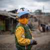 一个小男孩戴着口罩走过肯尼亚内罗毕的一个非正式定居点。