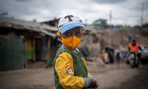A young boy wears a face mask as he walks through Mathare, an informal settlement in Nairobi, Kenya.