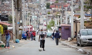 A man kicks a soccer ball up the street during lockdown in Alexandra Township, Johannesburg.
