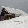 一名不丹妇女在屋顶上安装太阳能电池板。
