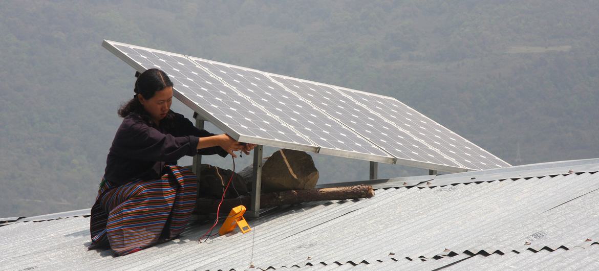 A woman installs solar panels on a roof in Bhutan.