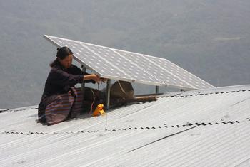 一名不丹妇女在屋顶上安装太阳能电池板。