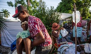 8月14日海地发生地震后，一名男子在一家医院等待治疗时被移到一张临时床上。