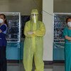 一名女医生身穿全套防护服，带领一群志愿医疗专业人员在菲律宾一家社区医院为新冠肺炎患者和被调查者提供服务。