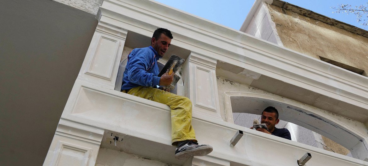 Dos hombres trabajan en la renovación de un edificio en  la ciudad de Tirana, la capital de Albania.