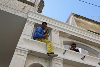 Dos hombres trabajan en la renovación de un edificio en  la ciudad de Tirana, la capital de Albania.