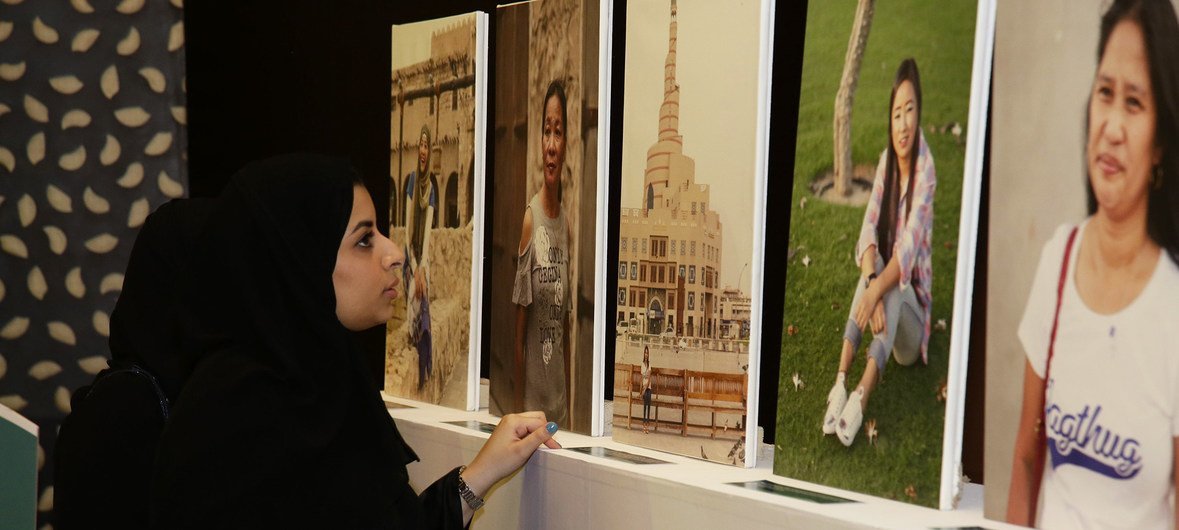إمرأة تتجول في معرض يحوي صورا لعاملات منزليات في قطر.