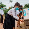 مجموعة من الأطفال في مدرسة في كمبوديا يغسلون أيديهم في مرفق للغسيل أعدته اليونيسف.