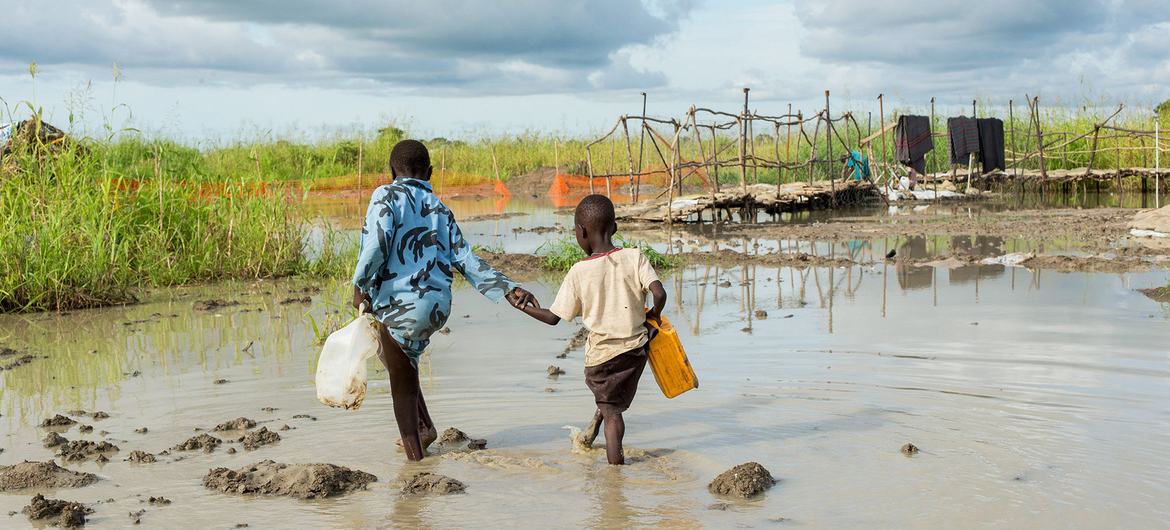 Crianças deslocadas caminham em área inundada no Sudão do Sul. 