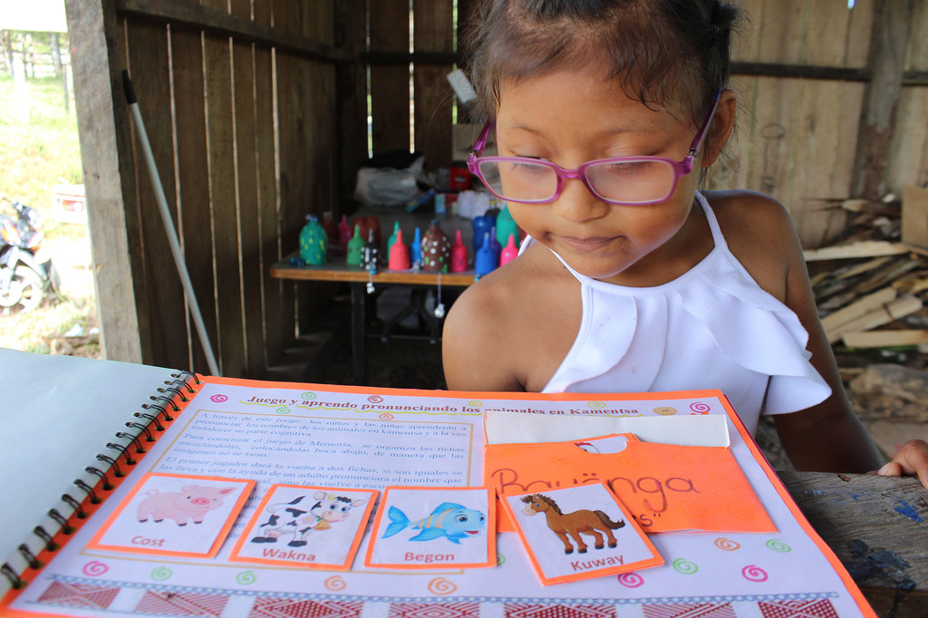 Una niña indígena contempla uno de los cuadernos Kametsa elaborados por Deisy.