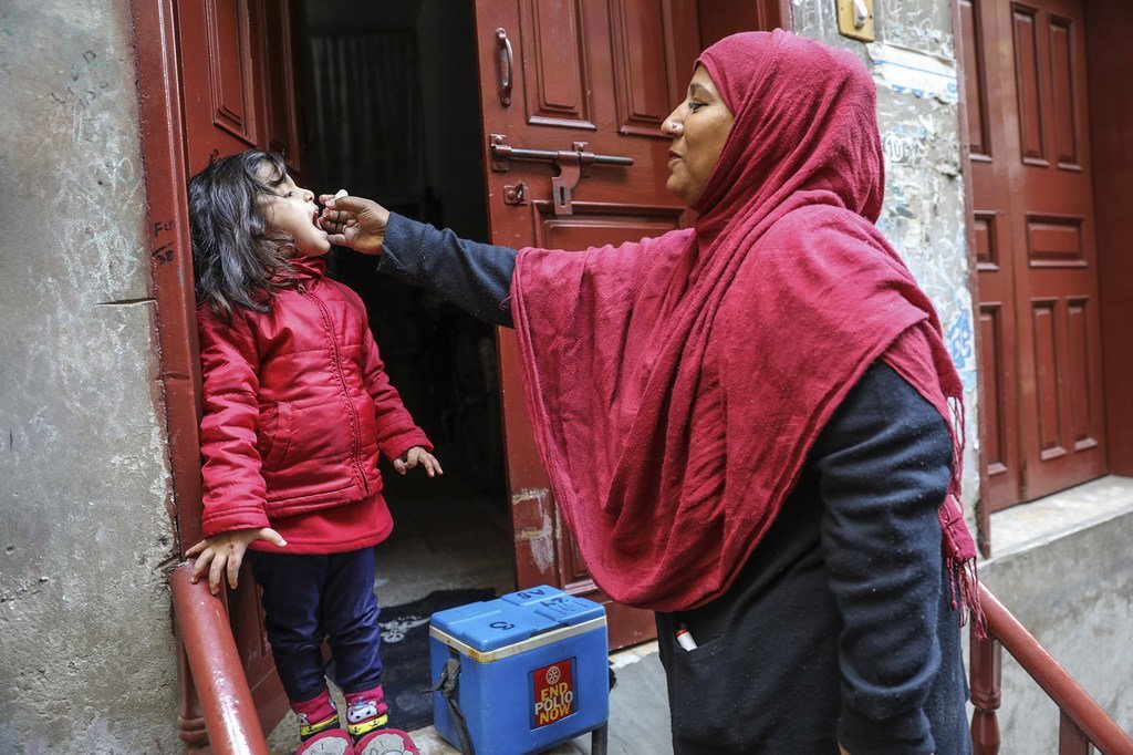 Un agent de santé vaccine une fillette de 4 ans contre la polio à la porte de sa maison dans la ville de Lahore, dans la province du Punjab, au Pakistan.