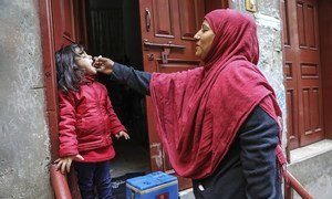 Un agent de santé vaccine une fillette de 4 ans contre la polio à la porte de sa maison dans la ville de Lahore, dans la province du Punjab, au Pakistan.