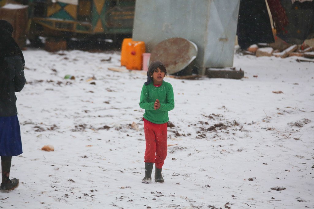 Un enfant marche dans la neige dans un camp de fortune pour familles déplacées dans le nord-ouest de la Syrie.