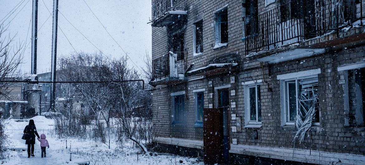 Pessoas caminham do lado de fora de um prédio residencial destruído por bombardeios em Marinka, Donetsk Oblast, Ucrânia.
