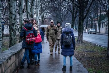 Soldados e estudantes caminham em uma rua em Krasnohorivka, Donetsk Oblast, Ucrânia.