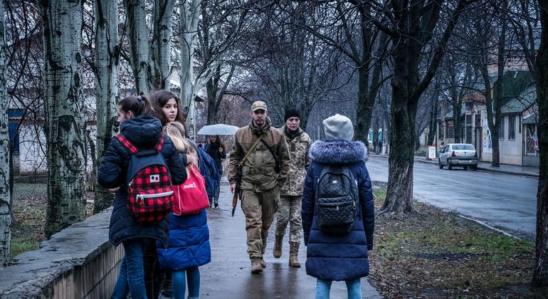 Soldados e estudantes caminham em uma rua em Krasnohorivka, Donetsk Oblast, Ucrânia.