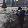 纽约东河边，一位戴着口罩的女性正在查看手机。