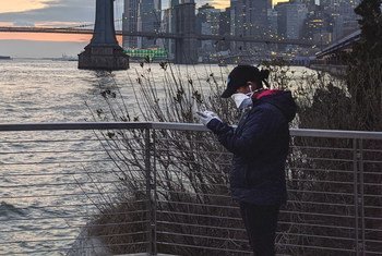 纽约东河边，一位戴着口罩的女性正在查看手机。