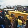 वर्ष 1985 में नस्लीय भेदभाव के उन्मूलन के अन्तरराष्ट्रीय दिवस पर दक्षिण अफ़्रीकी पुलिस द्वारा मारे गए लोगों के ताबूतों को ले जा रहे शोकाकुल लोग. 