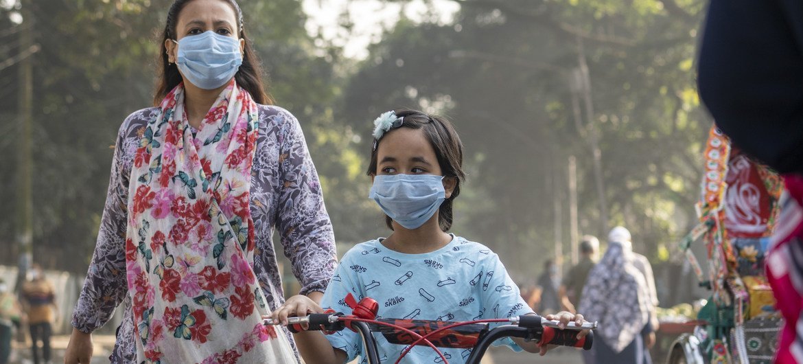 Una niña y su madre usan mascarillas para moverse por las calles de Bangladesh, una escena cotidiana de la pandemia de COVID-19 que empezó a principios de 2020. 