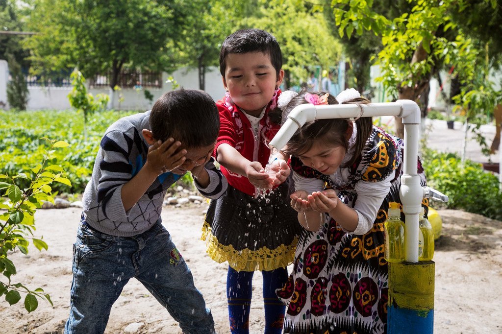乌兹别克斯坦费尔干纳地区的古利斯坦村，儿童在新安装的自来水龙头前洗手和洗脸。(2018年图片）