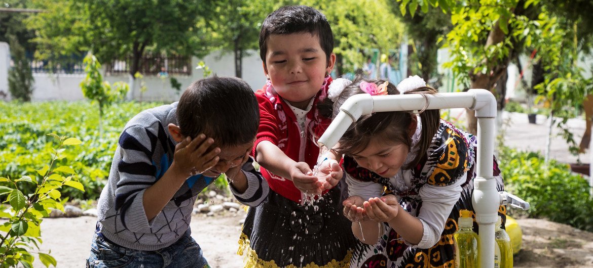 des enfants se lavent les mains et le visage à une nouvelle installation d'eau au village de Gulistan dans la région de Fergana au Uzbekistan