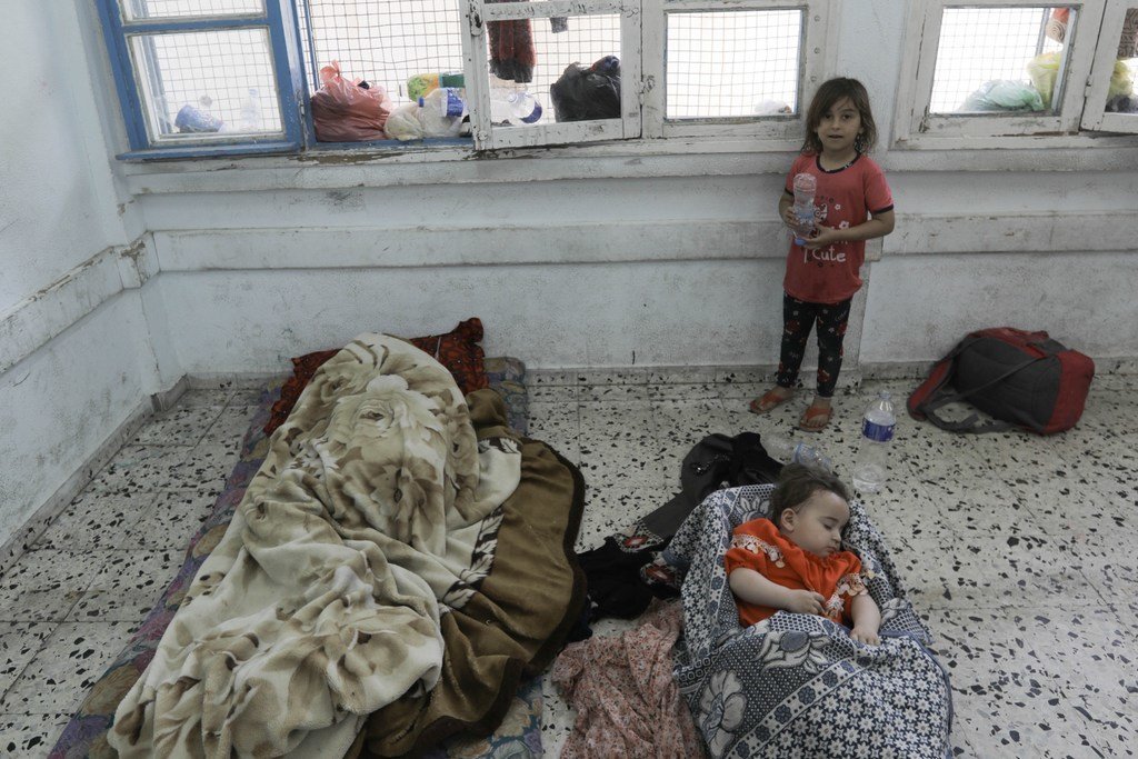 Un enfant regarde un bébé dormir dans une salle de classe de l'UNRWA à Gaza.