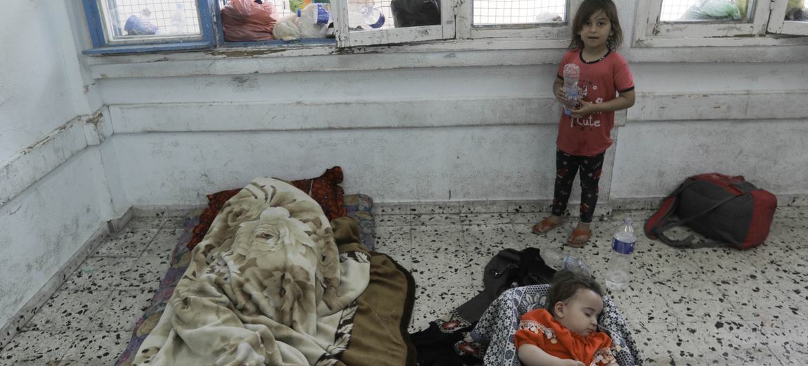 Una niña mira a sus hermanos dormir en el piso de un aula de una escuela de la UNRWA en Gaza