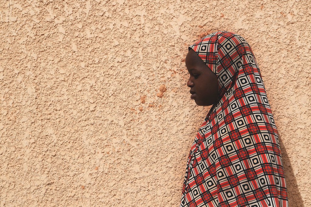 一名遭受虐待的10岁尼日尔女孩站在家门口。