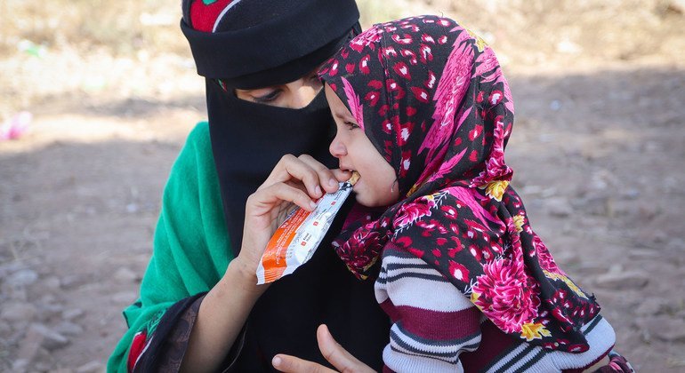 أم تطعم ابنتها بالبسكويت المغذي الذي حصلت عليه من مركز صحي متنقل في اليمن.